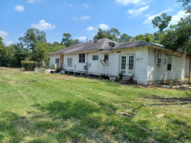 rear view of house with french doors and a lawn