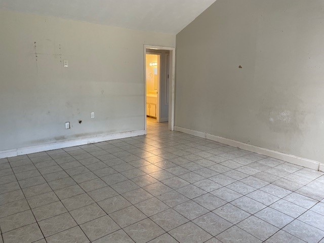 tiled empty room with lofted ceiling