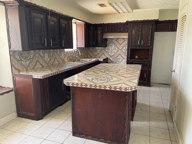 kitchen with light tile patterned floors, sink, tasteful backsplash, and a kitchen island