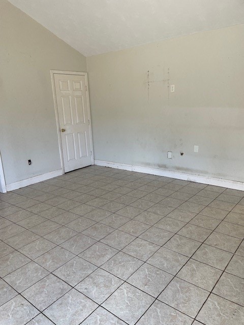 tiled spare room featuring lofted ceiling