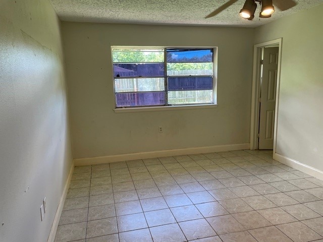 spare room with ceiling fan, a textured ceiling, and light tile patterned floors