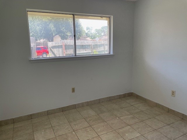 tiled spare room with a healthy amount of sunlight