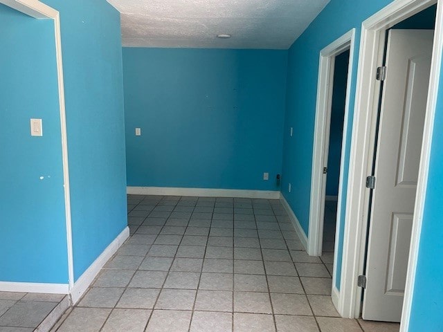 empty room featuring a textured ceiling and light tile patterned floors