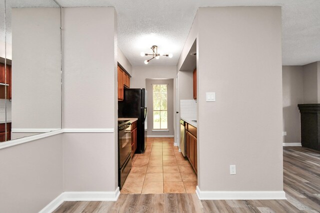 kitchen with a textured ceiling, black electric range oven, and light tile patterned floors