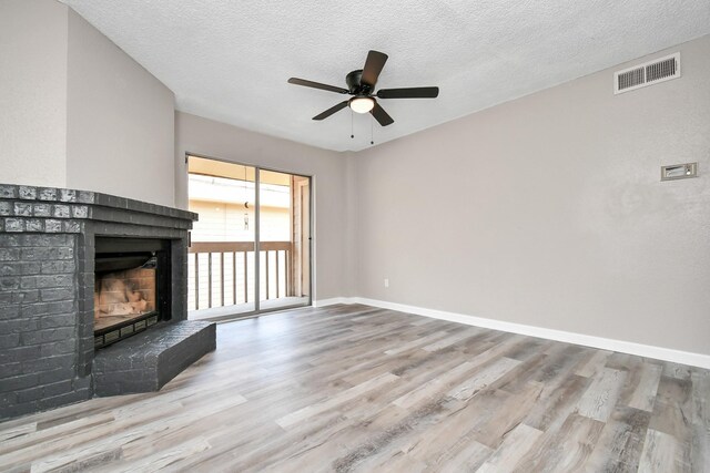 unfurnished living room featuring a fireplace, a textured ceiling, hardwood / wood-style flooring, and ceiling fan