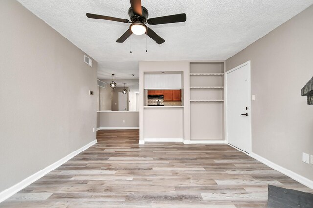 unfurnished living room featuring hardwood / wood-style floors, ceiling fan, and a textured ceiling