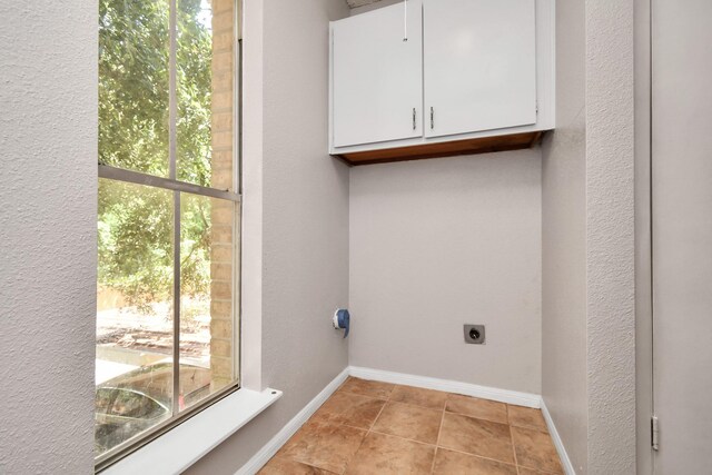 laundry area with cabinets, light tile patterned floors, and hookup for an electric dryer