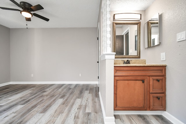 bathroom with wood-type flooring, vanity, a textured ceiling, and ceiling fan