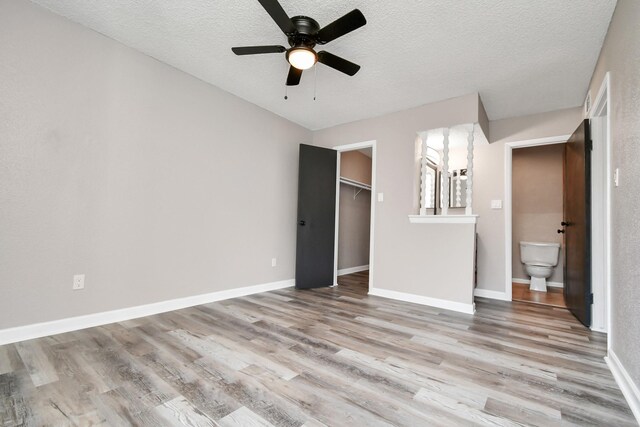 unfurnished bedroom with a closet, ceiling fan, hardwood / wood-style flooring, and a spacious closet