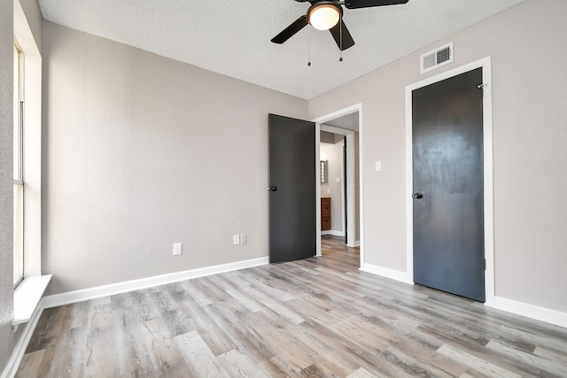 empty room with ceiling fan, light hardwood / wood-style floors, and a textured ceiling