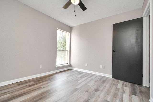 spare room featuring ceiling fan, light hardwood / wood-style floors, and a textured ceiling