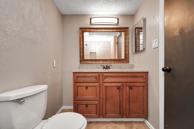 bathroom featuring tile patterned floors, vanity, toilet, and a textured ceiling