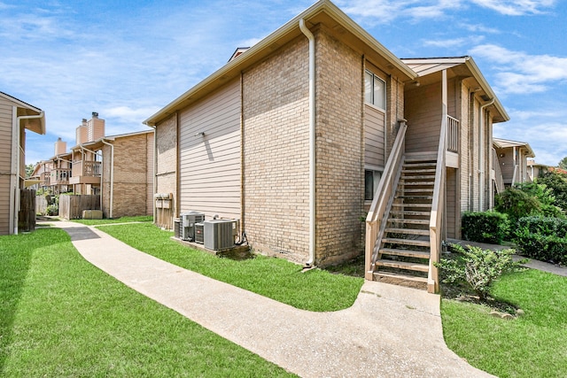 view of side of property with cooling unit and a lawn