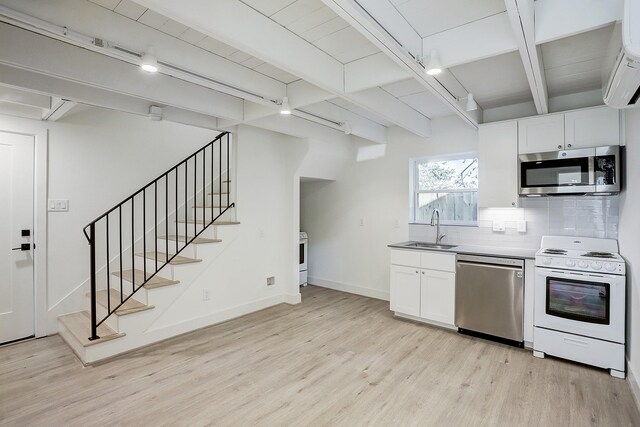 kitchen with appliances with stainless steel finishes, decorative backsplash, sink, beamed ceiling, and light wood-type flooring