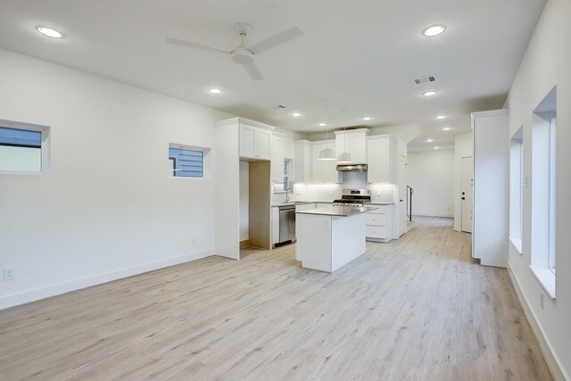 kitchen featuring a center island, light wood-type flooring, ceiling fan, stove, and white cabinets