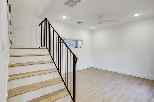 stairs featuring hardwood / wood-style flooring and ceiling fan