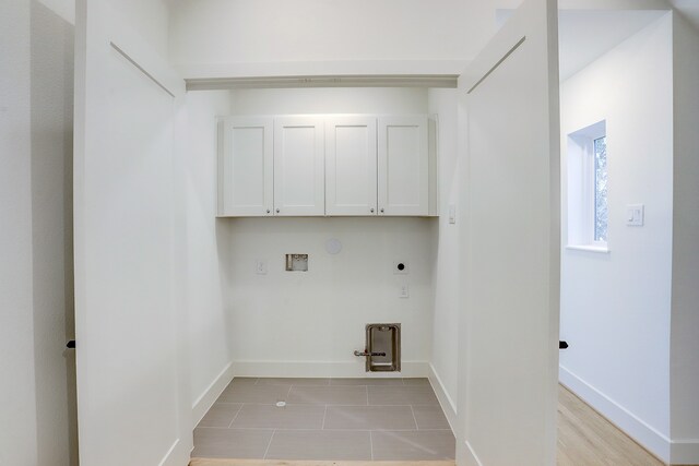 washroom with light hardwood / wood-style flooring, hookup for a gas dryer, washer hookup, cabinets, and hookup for an electric dryer