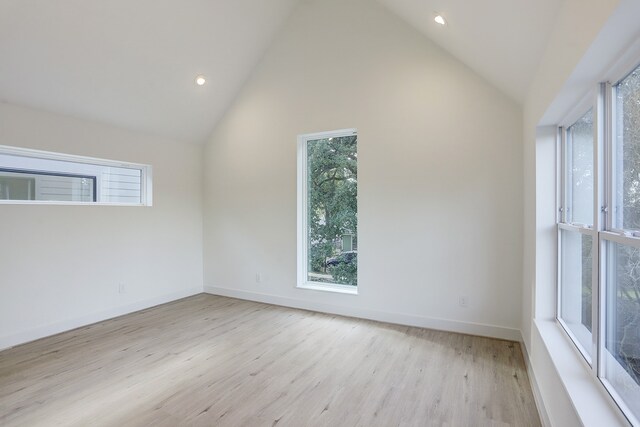 additional living space featuring light wood-type flooring and high vaulted ceiling