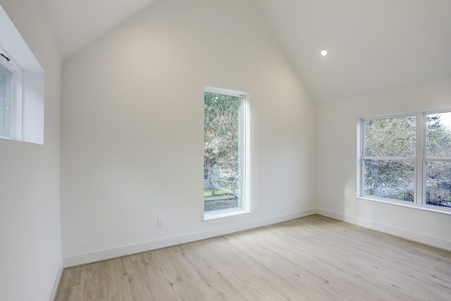 unfurnished room featuring light wood-type flooring, high vaulted ceiling, and a healthy amount of sunlight