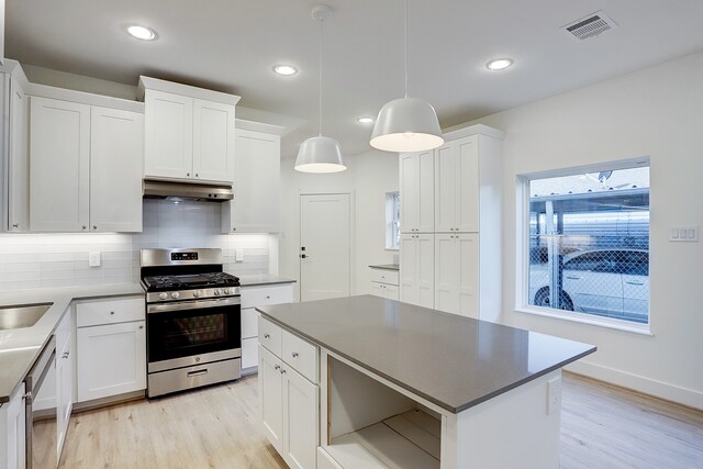 kitchen featuring tasteful backsplash, white cabinets, light hardwood / wood-style floors, decorative light fixtures, and stainless steel appliances