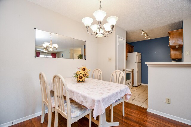 dining area featuring baseboards, rail lighting, wood finished floors, and a notable chandelier