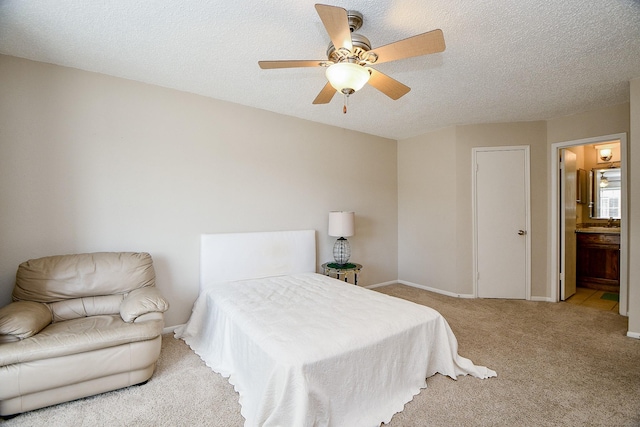 carpeted bedroom featuring baseboards, ceiling fan, ensuite bathroom, and a textured ceiling