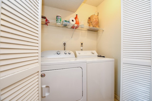 clothes washing area with washing machine and clothes dryer, a textured ceiling, and laundry area