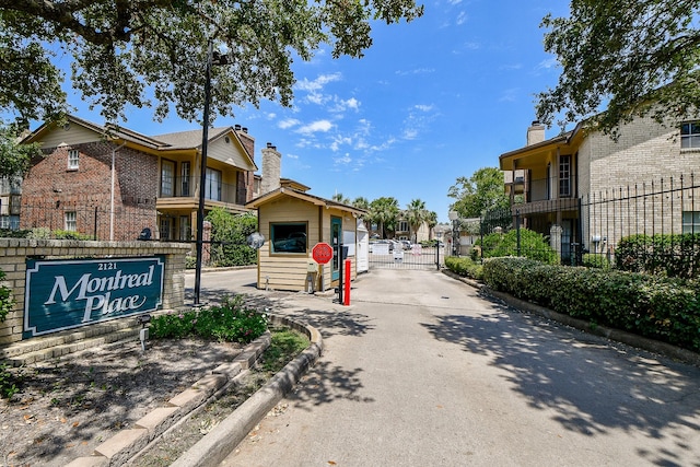 view of road with a residential view, a gated entry, curbs, a gate, and traffic signs