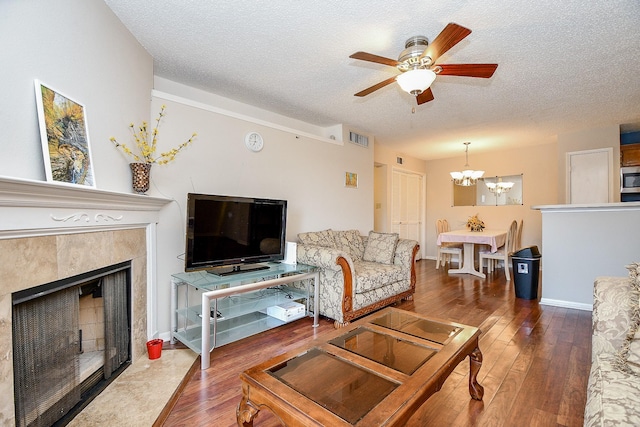 living room featuring a textured ceiling, visible vents, ceiling fan with notable chandelier, and hardwood / wood-style floors