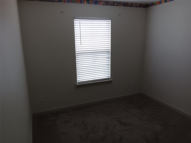unfurnished room with a wealth of natural light, carpet flooring, and baseboards