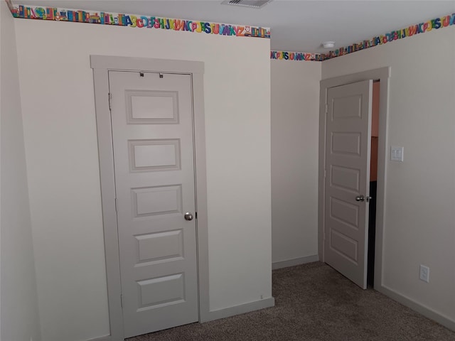 unfurnished room with carpet flooring, visible vents, and baseboards