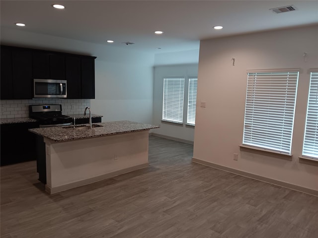 kitchen featuring visible vents, decorative backsplash, appliances with stainless steel finishes, a sink, and dark cabinetry