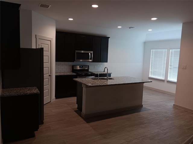 kitchen with visible vents, appliances with stainless steel finishes, a sink, dark cabinetry, and backsplash