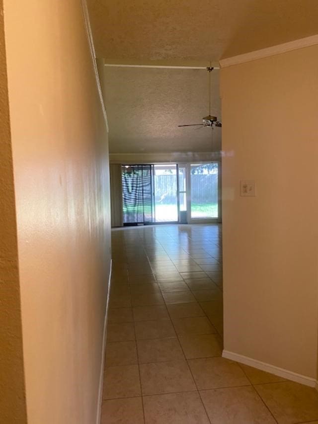 corridor with tile patterned flooring, a textured ceiling, and ornamental molding