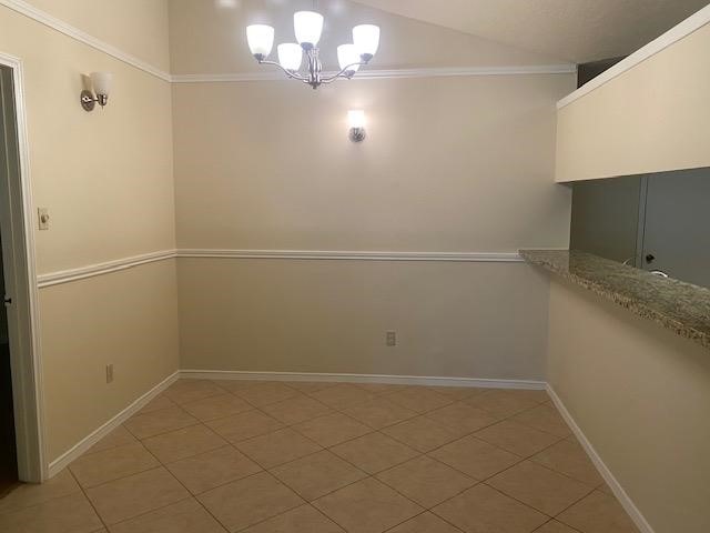 unfurnished dining area featuring tile patterned floors, a notable chandelier, and ornamental molding