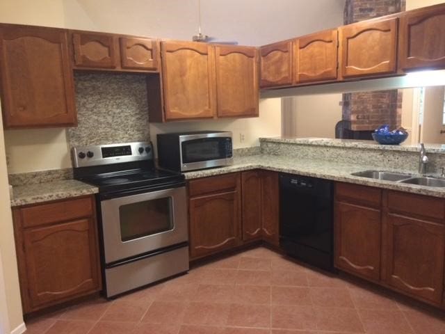 kitchen featuring sink, stainless steel appliances, dark tile patterned flooring, and light stone countertops