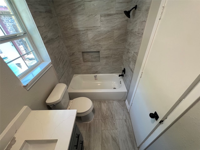 full bathroom featuring tiled shower / bath, vanity, and toilet