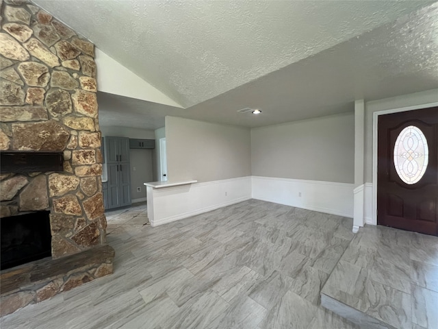 interior space featuring a fireplace, a textured ceiling, and lofted ceiling