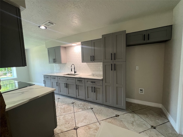 kitchen with sink, decorative backsplash, a textured ceiling, light tile patterned floors, and gray cabinets