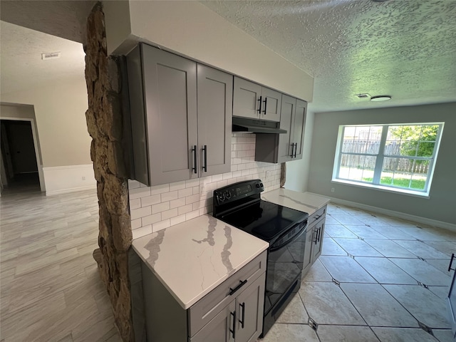 kitchen with backsplash, electric range, light stone counters, a textured ceiling, and gray cabinets