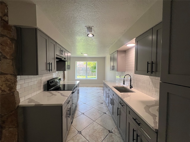 kitchen with sink, light stone counters, decorative backsplash, and black / electric stove