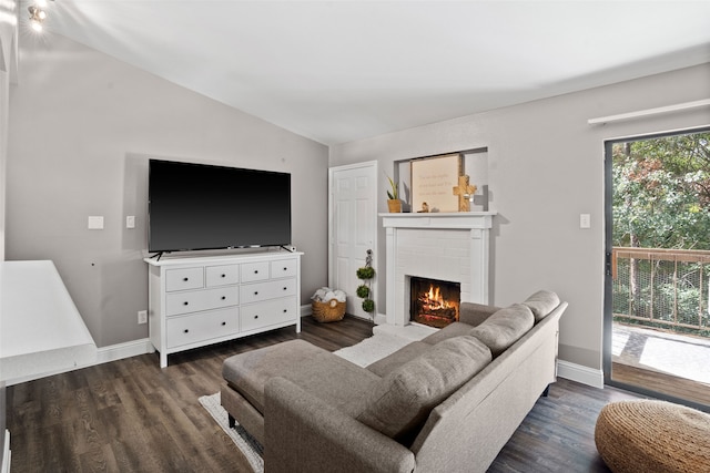 living room with vaulted ceiling, dark wood-type flooring, and a brick fireplace