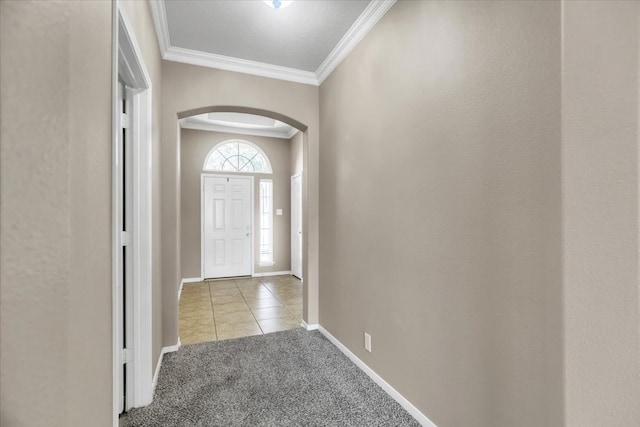 foyer entrance with ornamental molding and light carpet