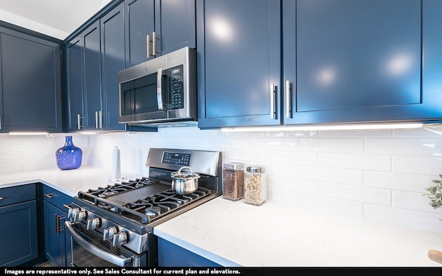 kitchen featuring gas range, blue cabinets, and backsplash