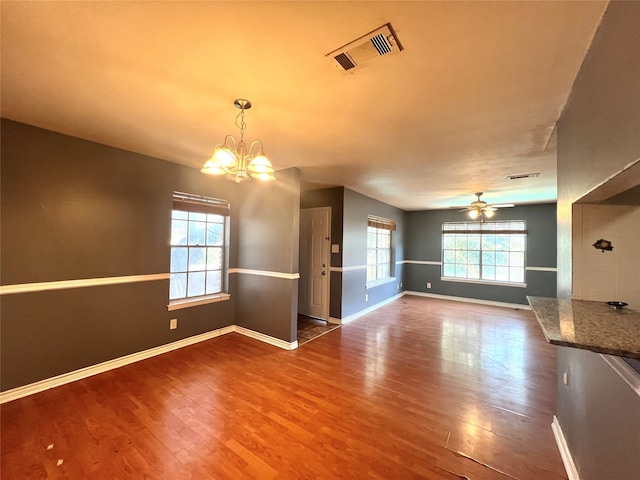 unfurnished living room with ceiling fan with notable chandelier and hardwood / wood-style flooring