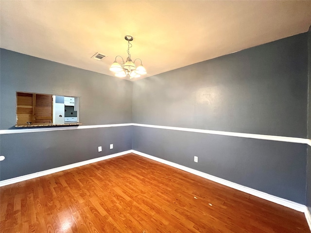 spare room featuring a notable chandelier and wood-type flooring