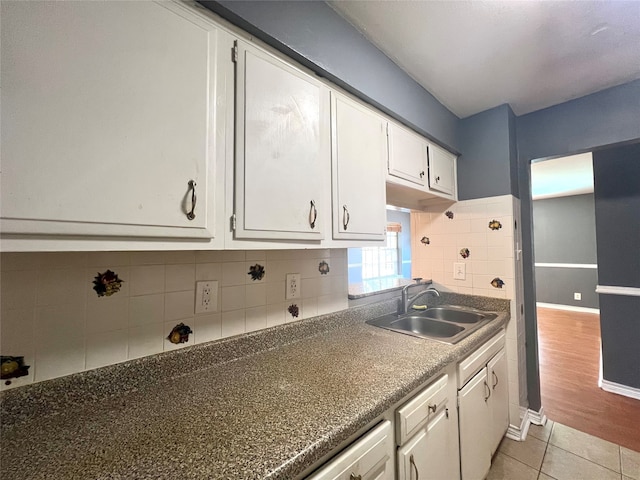 kitchen featuring sink, light hardwood / wood-style floors, decorative backsplash, and white cabinetry