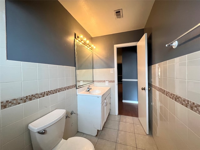 bathroom featuring toilet, tile patterned flooring, visible vents, and tile walls