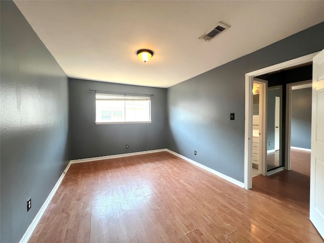 unfurnished room with wood finished floors, visible vents, and baseboards