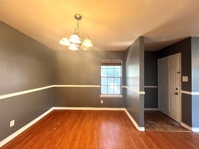 spare room with wood-type flooring and a notable chandelier